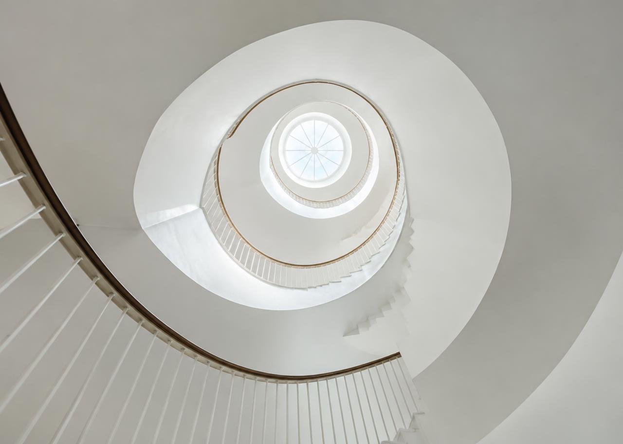 Spiral staircase rising toward a skylight